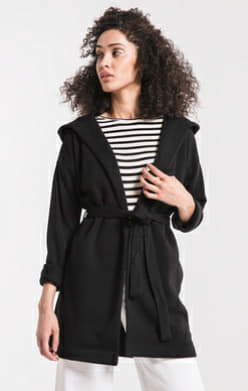 Woman wearing black fleece coatigan with hood, tie belt, and front pockets in relaxed fit