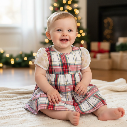 Baby girl wearing festive red, green, yellow and white plaid holiday dress with white puff sleeves featuring gold star appliqués, tiered skirt, size 18-24 months