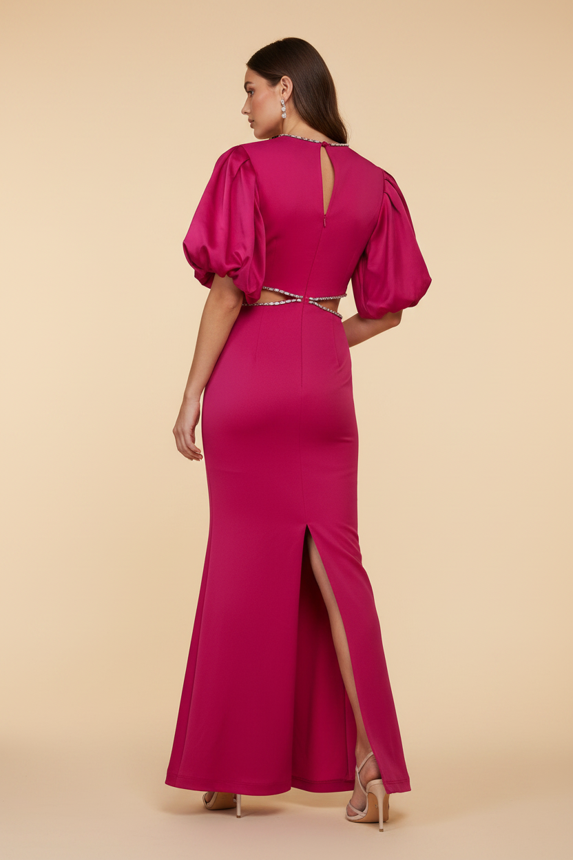 A woman shown from the back wearing a bright fuchsia maxi dress with puff sleeves, a high slit, and a small rhinestone-embellished waist detail, photographed against a plain beige studio background.