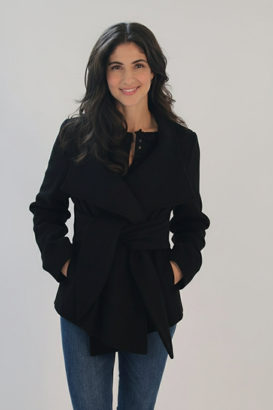 Woman wearing black Ciao Milano Helena tie-waist jacket with dramatic belted waist and convertible collar, styled over dark clothing