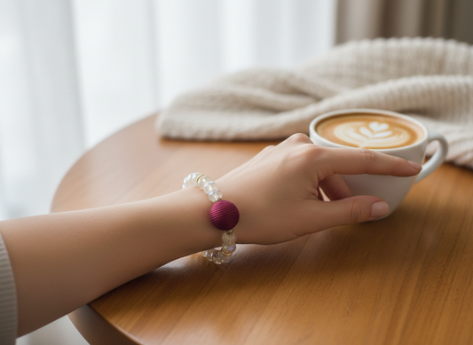 Woman wearing iridescent crystal stretch bracelet with burgundy wrapped ball centerpiece in elegant lifestyle setting