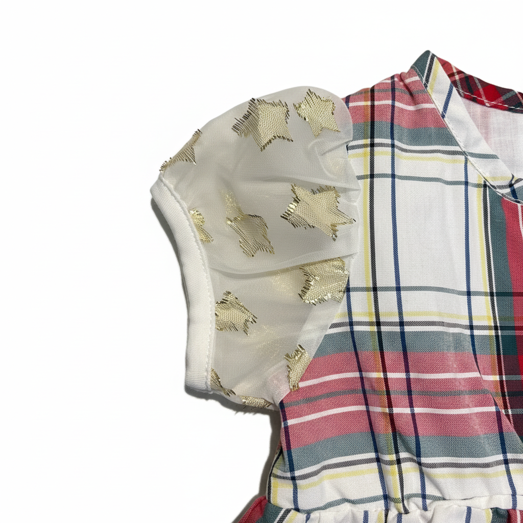 Close-up of white organza puff sleeve with gold metallic star appliqués on plaid holiday dress