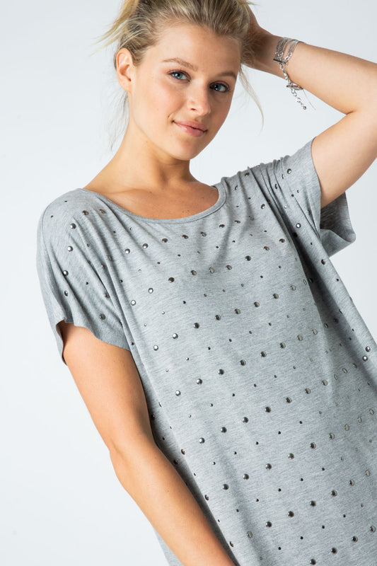 Woman wearing grey short sleeve top with allover silver stud embellishments and scoop neckline