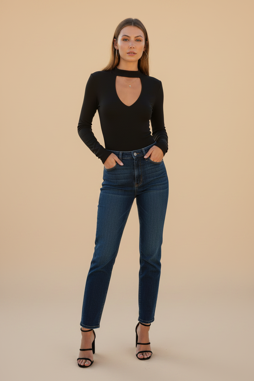 Woman in black choker neck deep V cutout ribbed bodysuit with dark wash jeans and strappy heels, minimalist beige studio hero photo