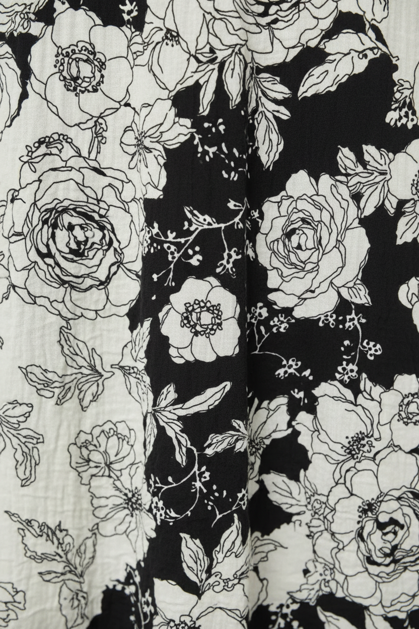 Close-up detail of black and cream floral print satin fabric, flowing maxi dress texture and drape