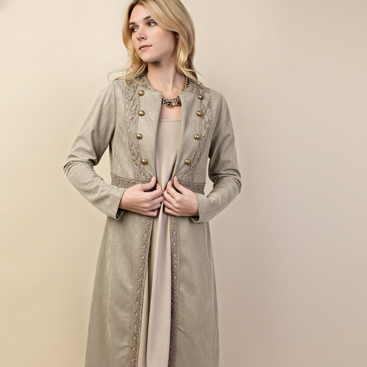 Woman wearing a long, light brown coat with decorative buttons on a beige background