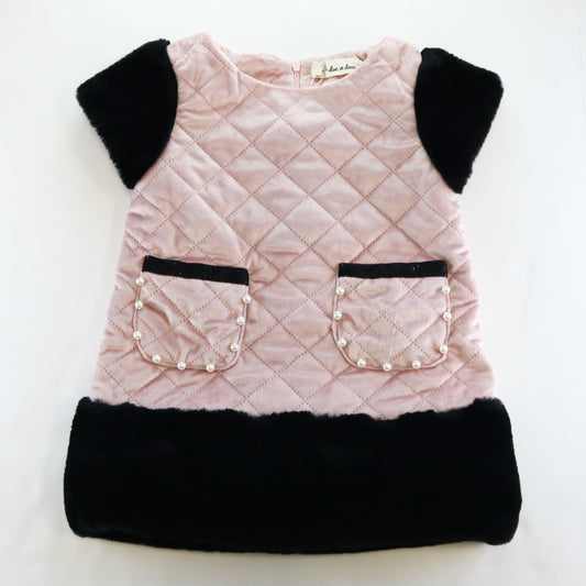A girls' faux suede quilted fur trim dress in pink with black accents and pockets on the front.