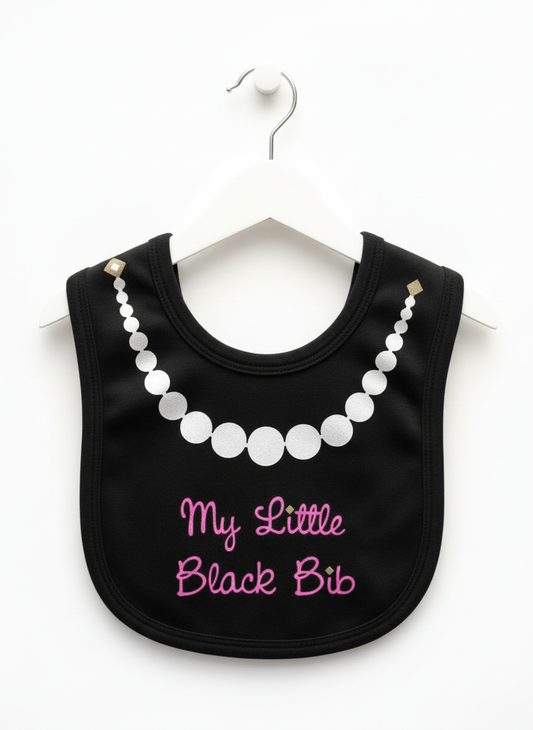 Black baby bib with white glitter pearl necklace graphic and hot pink glitter script text reading 'My Little Black Bib' hanging on white hanger against white background