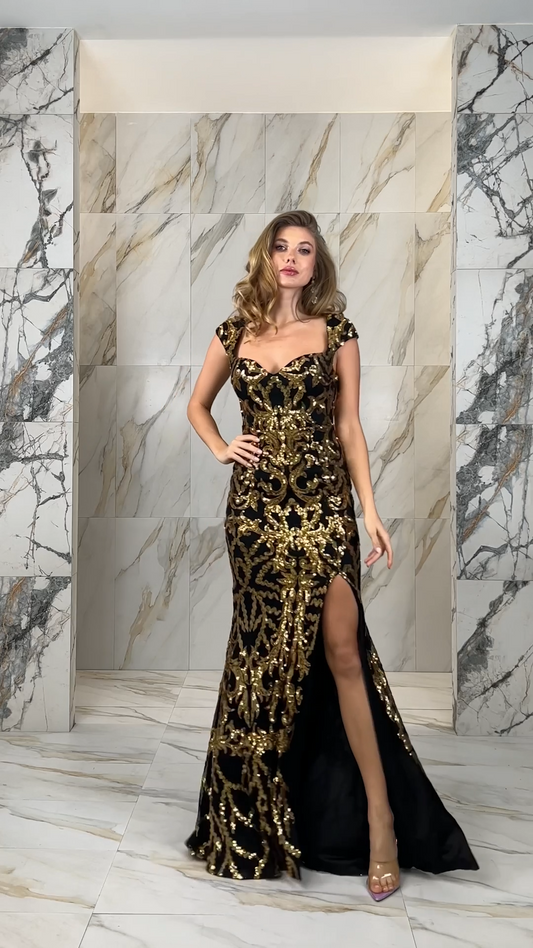 Woman wearing black gown with gold sequin embellishment, cap sleeves, and high slit, showcasing movement and sparkle in formal evening wear
