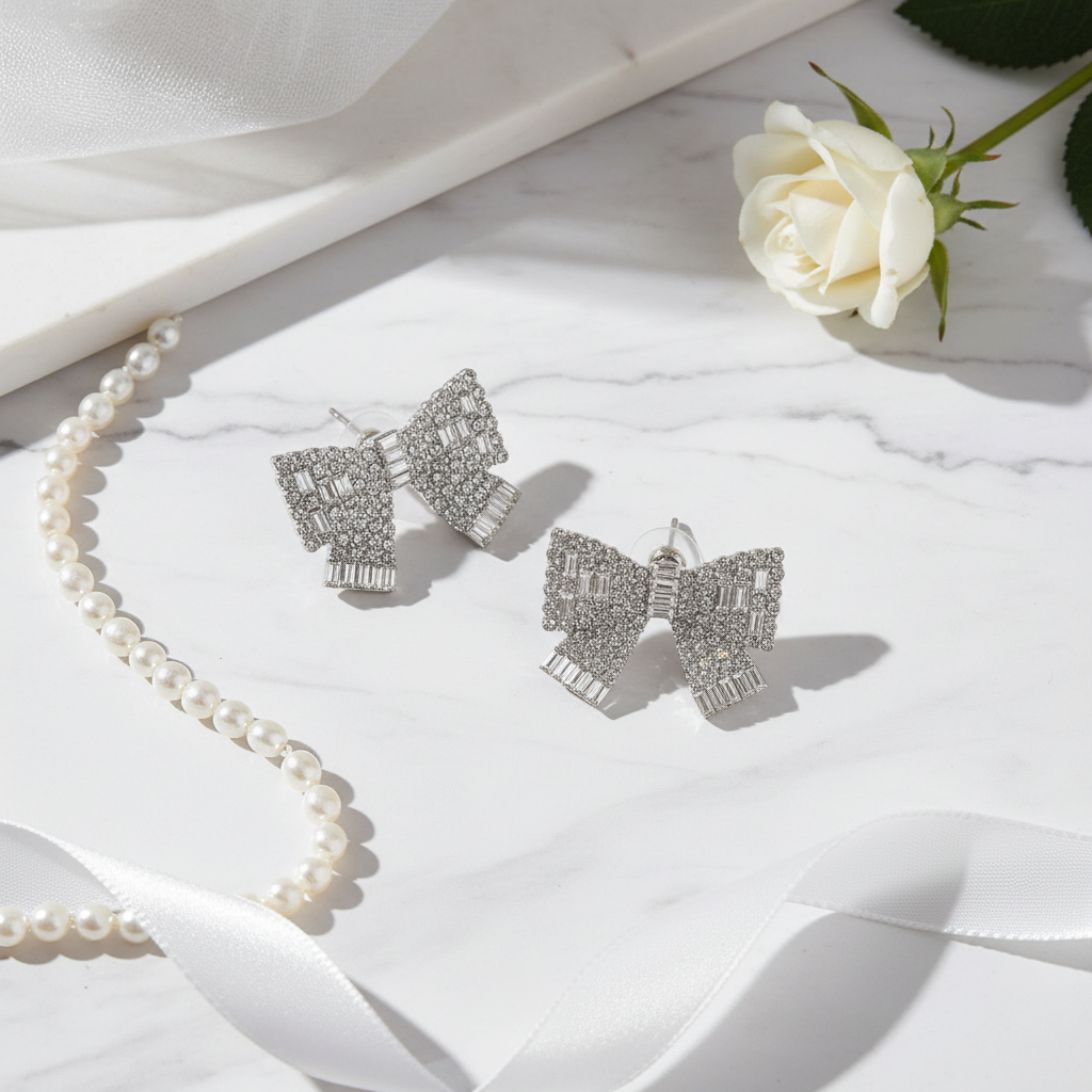 ilver rhinestone bow stud earrings on white marble with elegant minimal styling