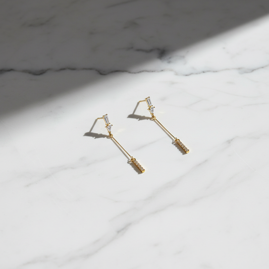 Upscale flat lay of gold CZ bar drop earrings on marble