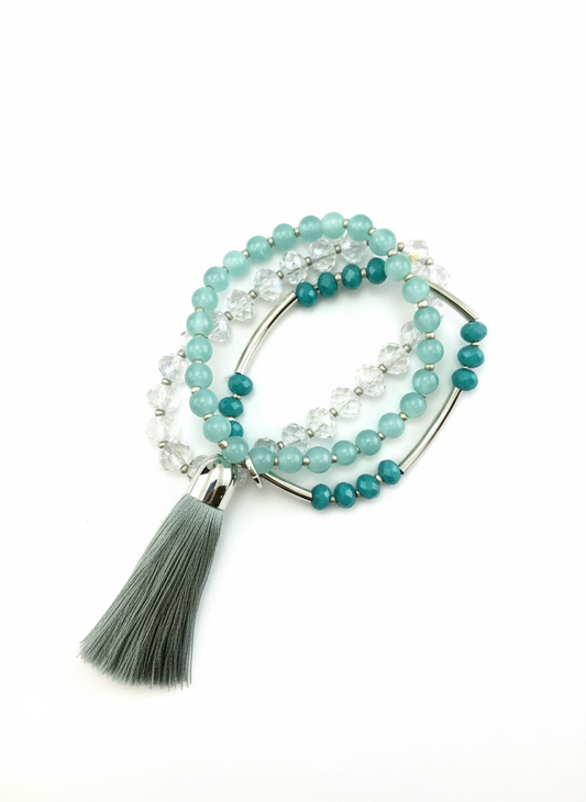 Three-piece turquoise and silver crystal stretch bracelet set with tassel arranged on white background - minimalist product photography