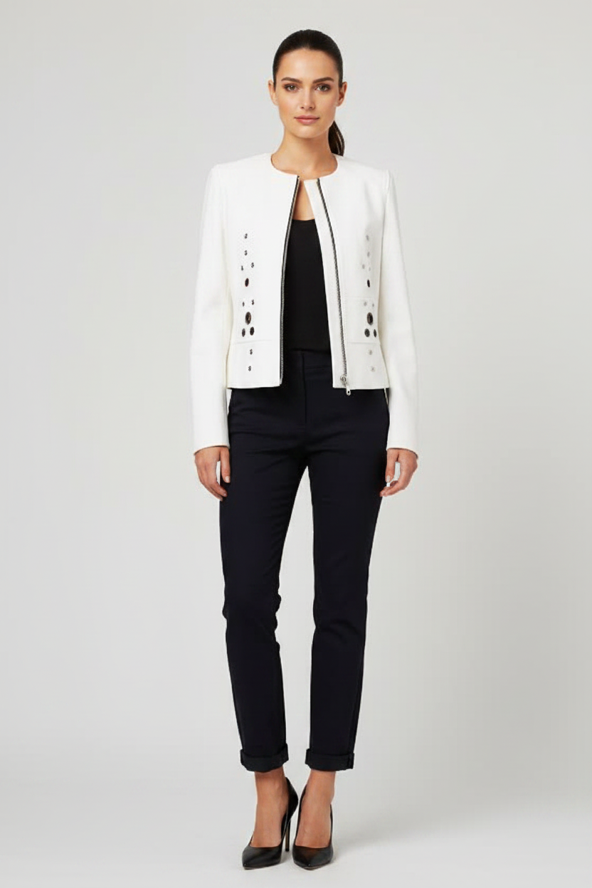 White structured collarless jacket clean studio editorial – asymmetric black grommet and eyelet embellishments on fitted tailored white zip jacket against seamless backdrop