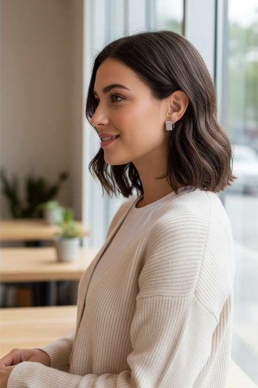 Woman wearing silver textured square open huggie earrings showing 0.5-inch geometric design in natural lifestyle setting with modern casual style