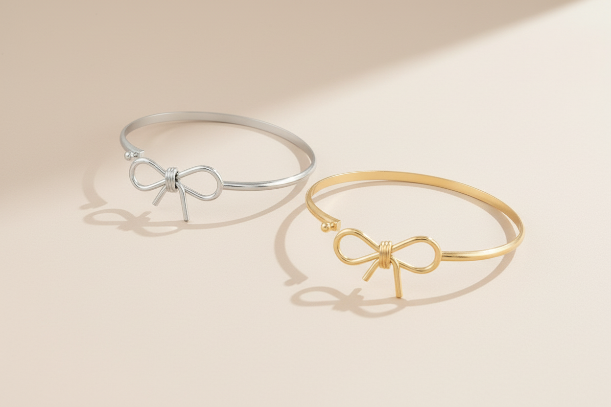 Two bracelets, one gold and one silver, with bow designs on a white background.
