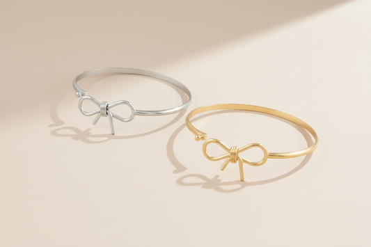 Two bracelets, one gold and one silver, with bow designs on a white background.
